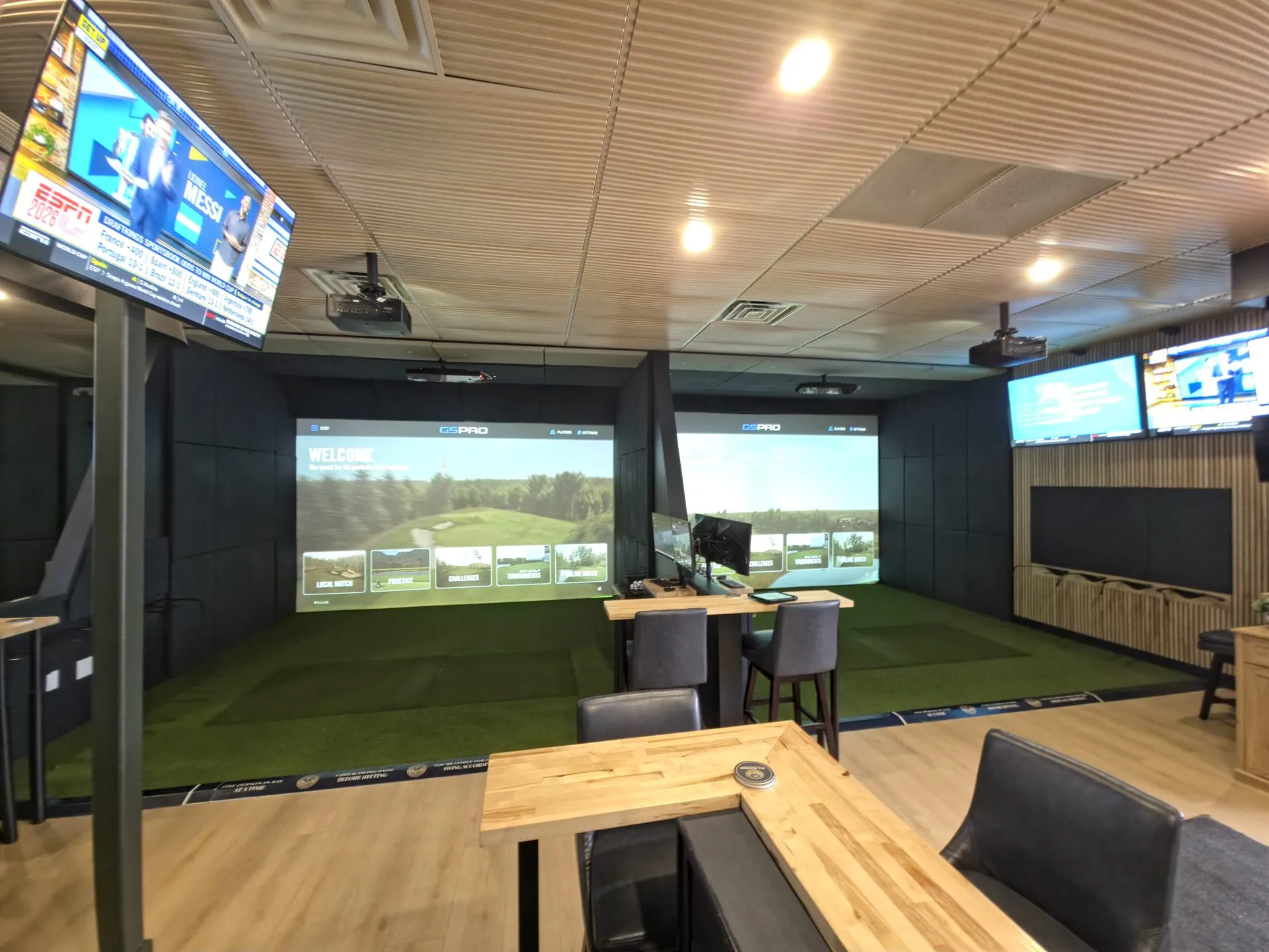 Two side-by-side golf simulator bays with GSPRO on the screens and bar seating at All Seasons Indoor Golf, Kansas City