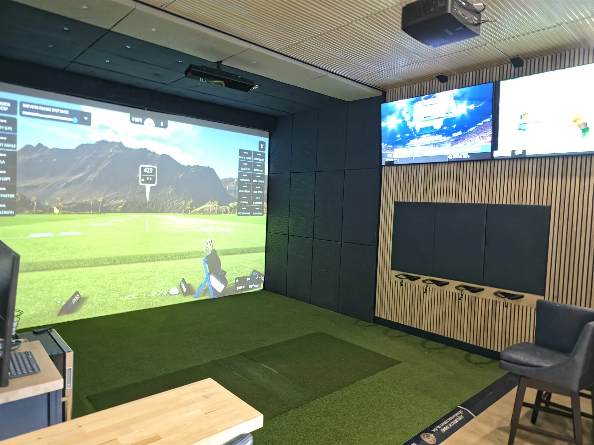Golf simulator hitting bay with a course on the large projection screen at All Seasons Indoor Golf, Kansas City