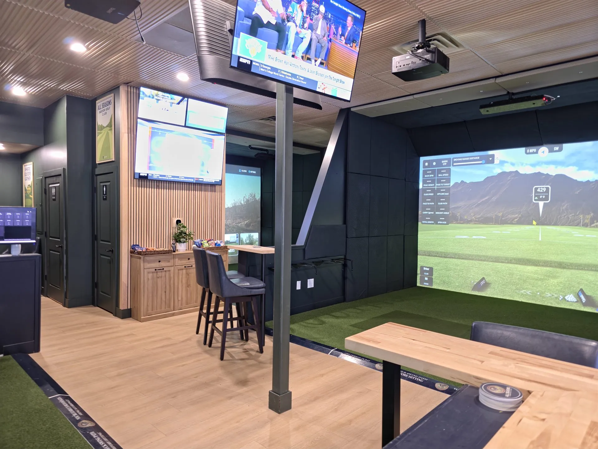 Golf simulator bay and lounge with bar-height seating and sports TVs at All Seasons Indoor Golf, Kansas City